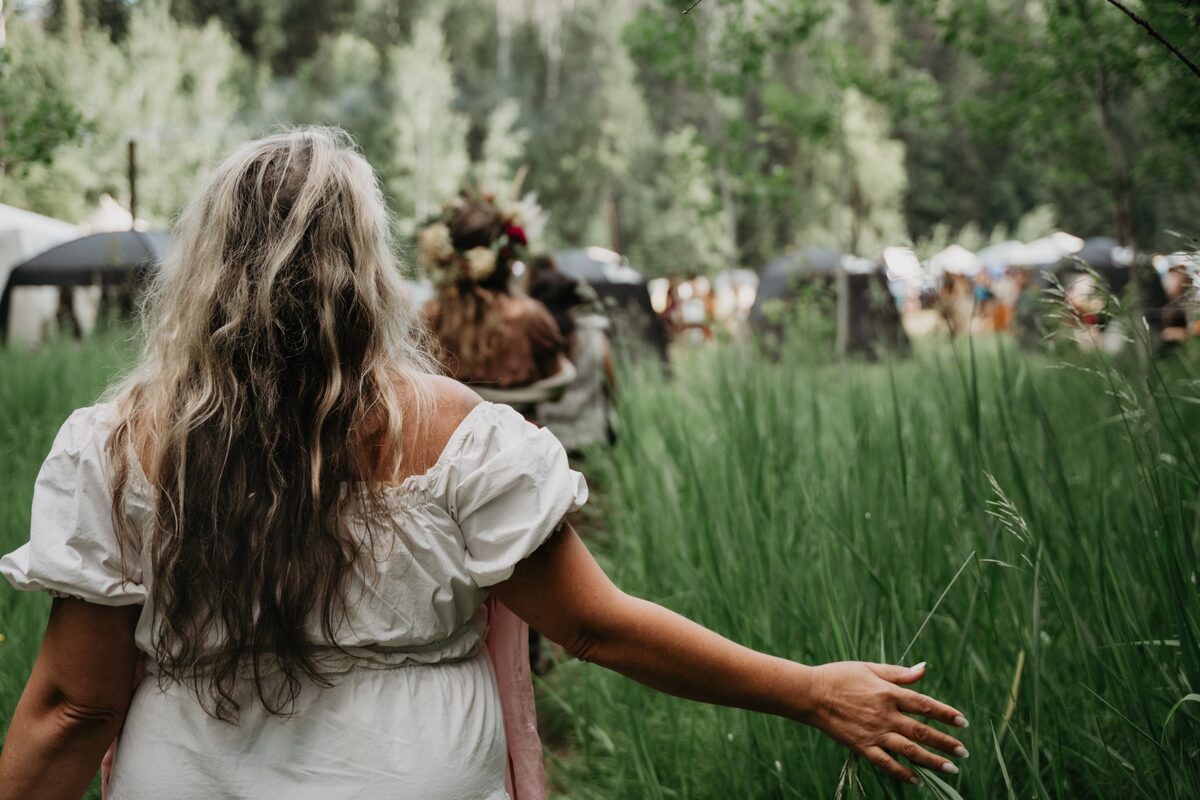 Woman reaching into the tall grass, long hair, open field