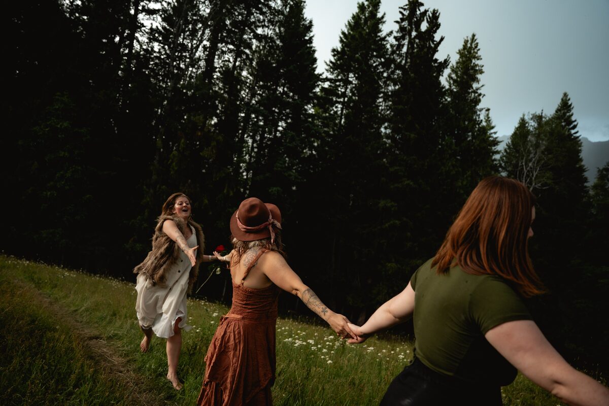 Women holding hands and running through a mountain meadow
